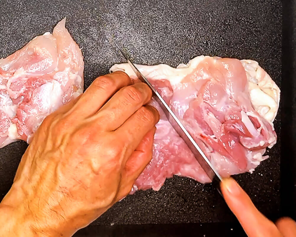 "Scoring chicken thigh with knife to shape it evenly."