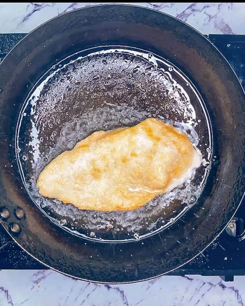 Chicken breast turning golden while searing in pan with oil."
