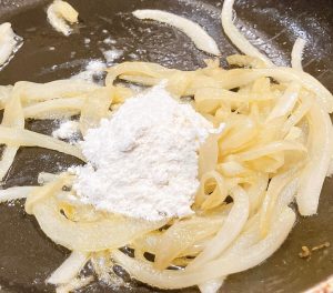 Flour added to softened onions to start gravy roux