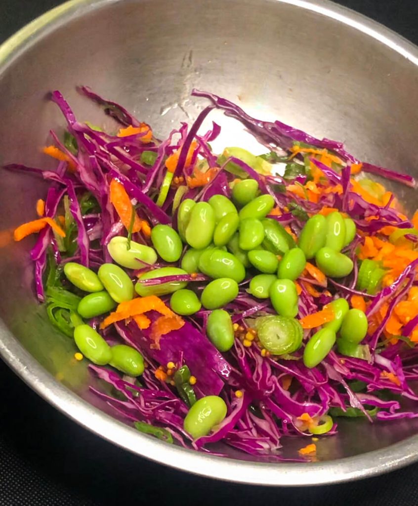 Colorful salad mix with red cabbage, carrot, and edamame in a stainless steel bowl.