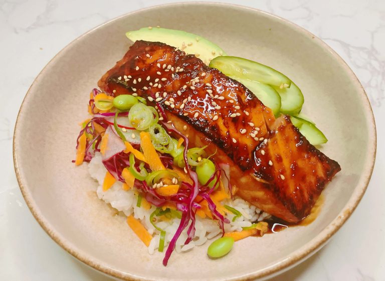 Ginger teriyaki salmon Bowl served with rice, avocado, cucumber, and colorful salad.