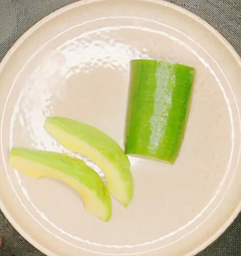Halved pieces of cucumber and avocado prepared for salmon bowl toppings.