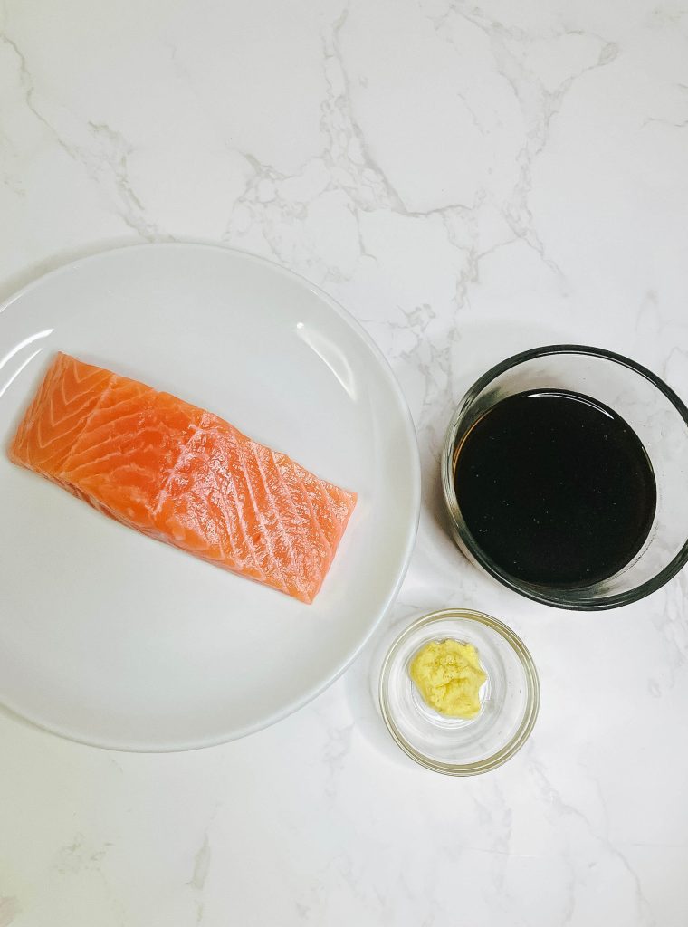 Ingredients for ginger teriyaki salmon: raw salmon fillet, grated ginger, and pantry teriyaki sauce.