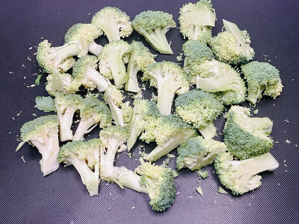 Raw broccoli florets arranged on a cutting board, prepped and ready for airfrying or oven roasting