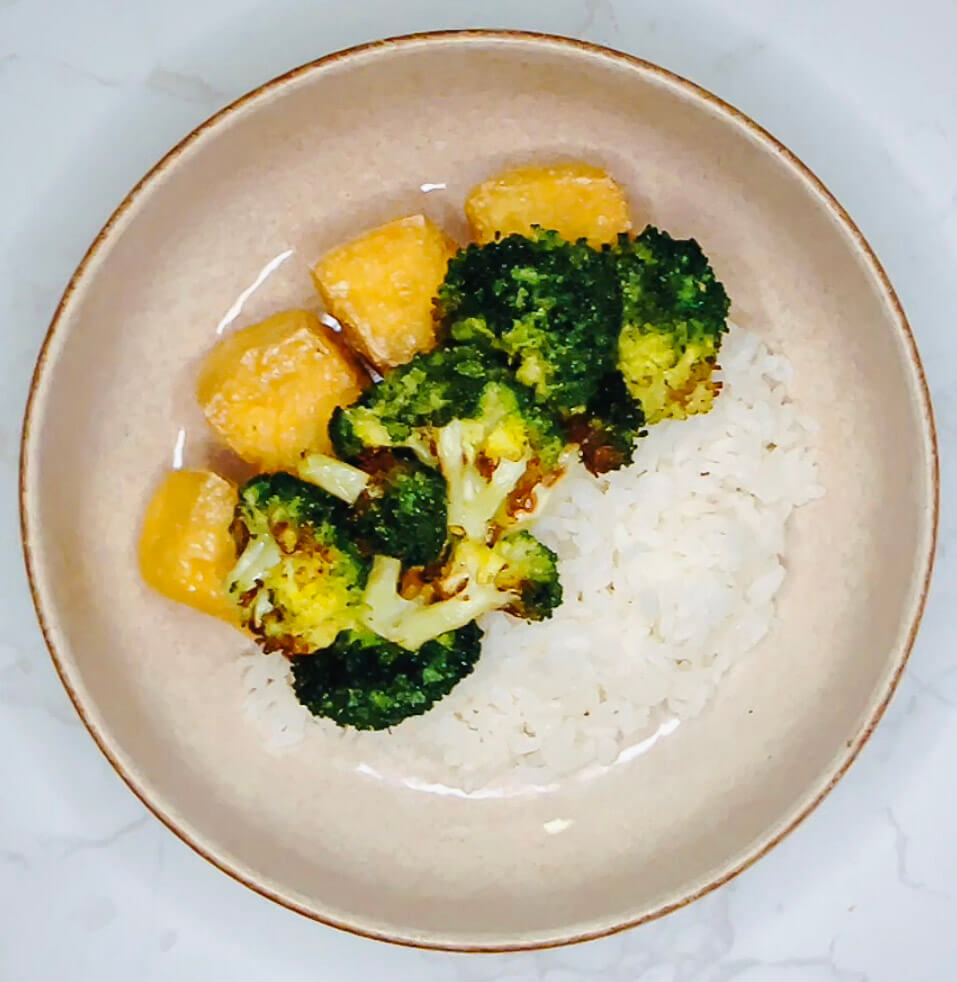 Crispy broccoli and tofu placed on top of steamed rice in bowl, ready for teriyaki glaze