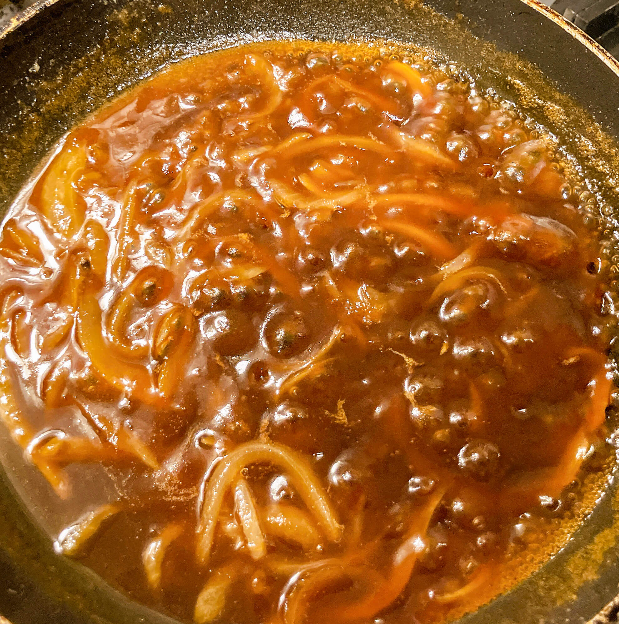 Simmering teriyaki gravy with onions in pan