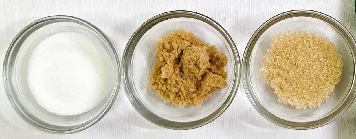 White, brown, and raw sugar in bowls