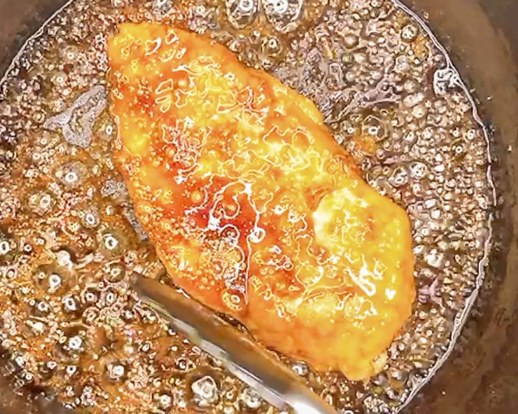 Close-up of chicken breast cooking in traditional teriyaki sauce reduction
