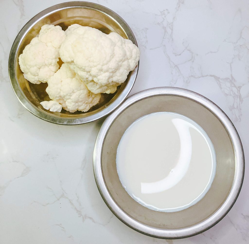 Fresh cauliflower florets and pouring cream prepared for a cauliflower mash variation.

