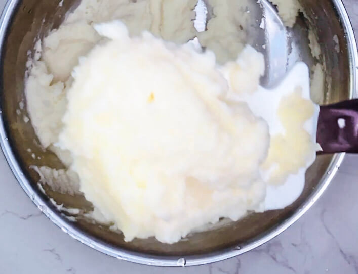 Finished mashed potatoes in a pot, smooth and fluffy, ready to be plated for bangers and mash.