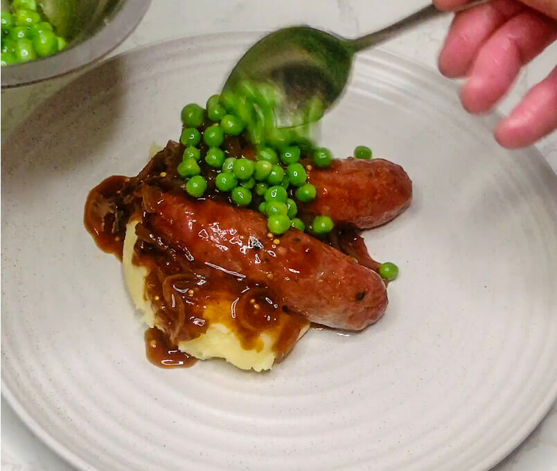 Adding steamed green peas to bangers and mash with teriyaki onion gravy for the finishing touch.