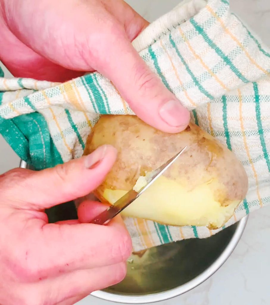 Peeling hot boiled potatoes by hand for restaurant-style mashed potatoes.