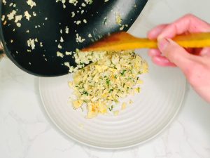 Plating freshly cooked cauliflower fried rice with egg and green onion, ready to serve with miso eggplant.