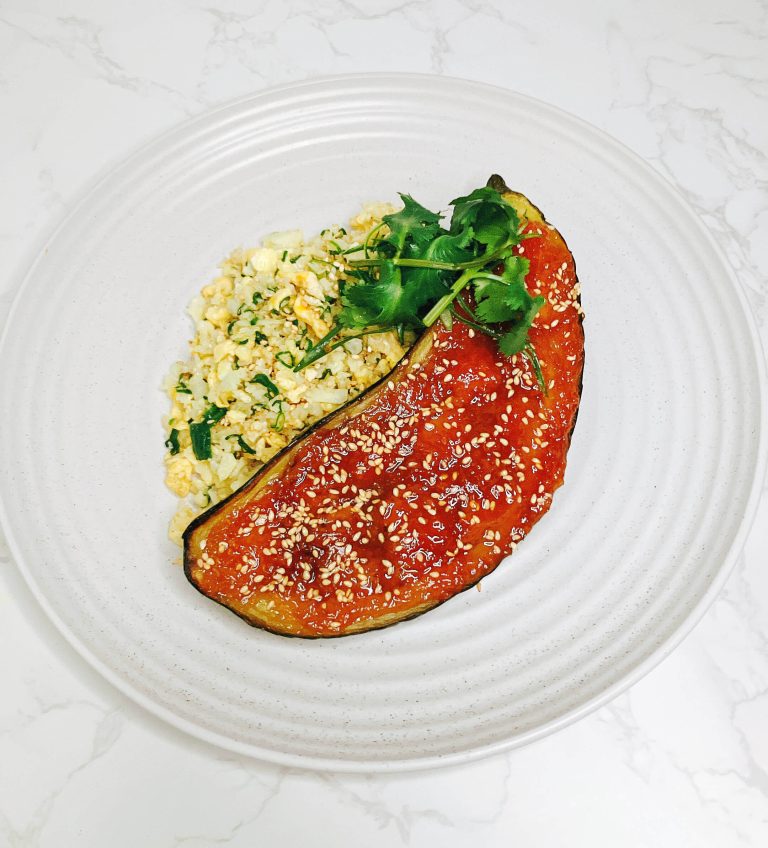 Top-down view of miso-glazed red eggplant served with cauliflower fried rice, garnished with spring onion and cilantro on a white plate
