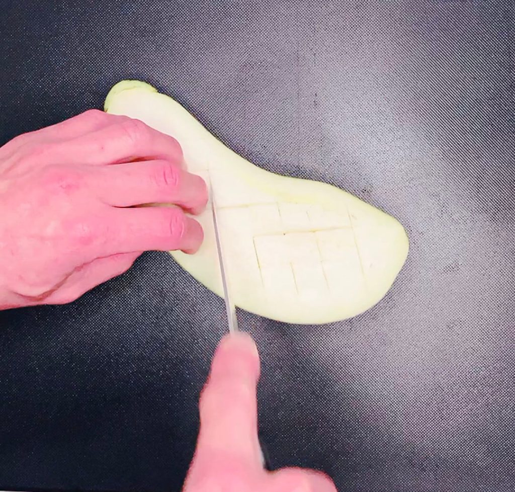 Scoring the cut side of an eggplant for cauliflower fried rice with miso eggplant. Title: