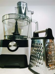 Food processor and box grater side by side for making keto cauliflower rice, showing two methods for ricing cauliflower