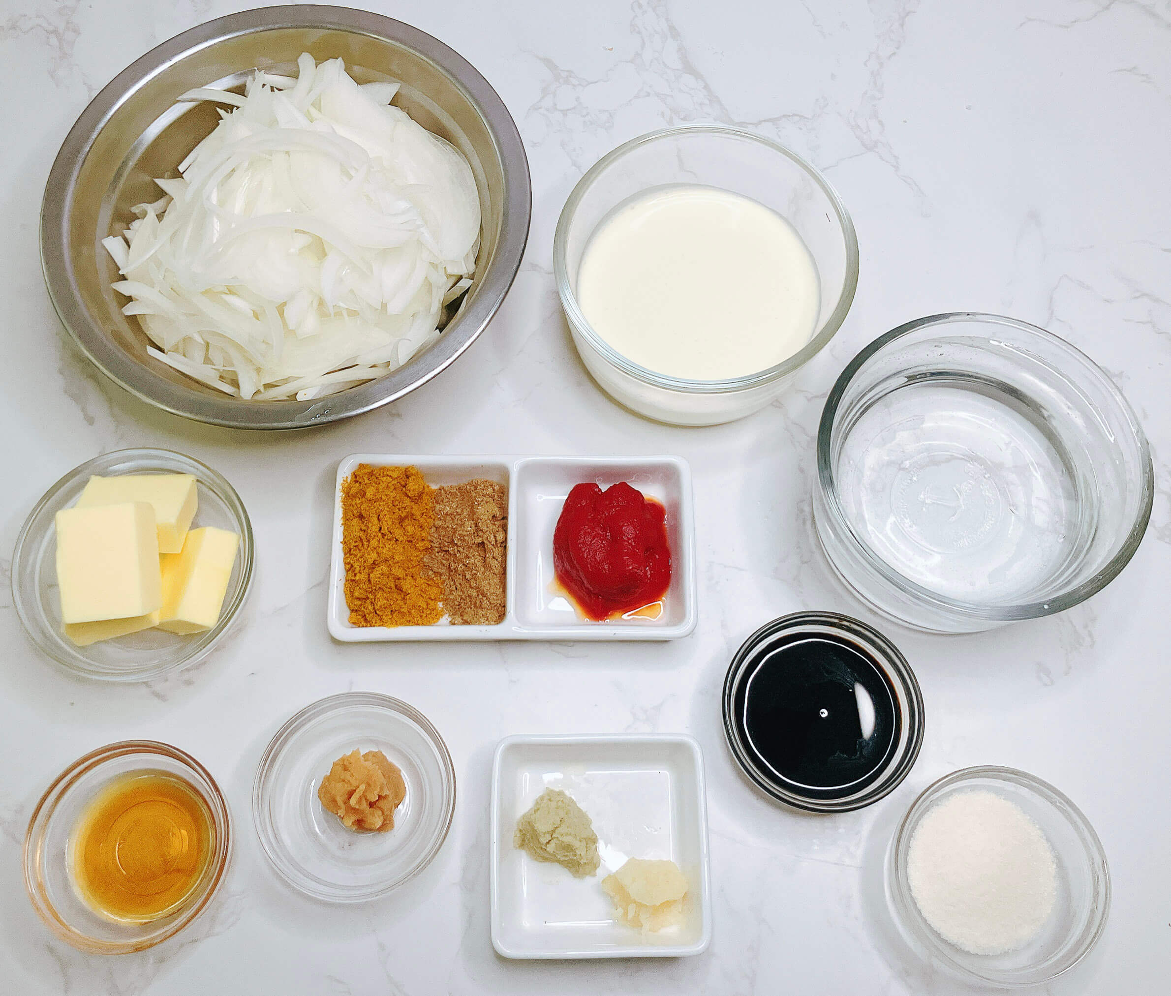 Keto curry sauce ingredients spread with butter, onion, garlic, ginger, curry powder, tomato paste, tamari, and coconut milk.