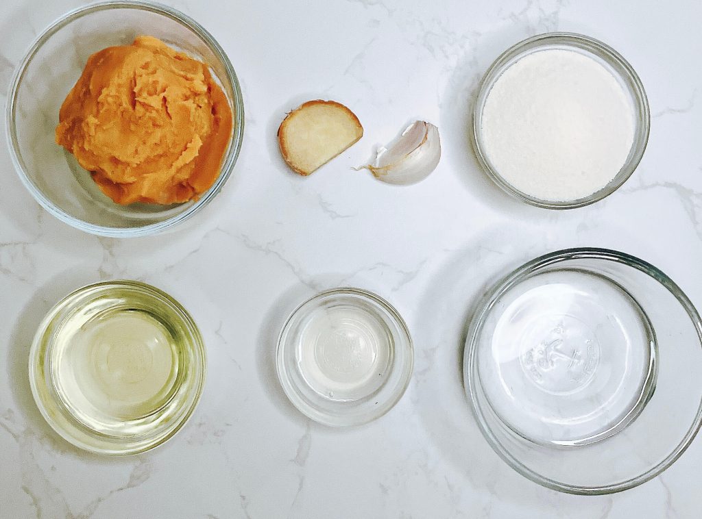 Keto miso sauce ingredients in bowls — miso paste, ginger, garlic, monk fruit sweetener, rice vinegar, oil, and water.
