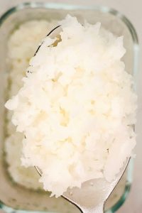 Microwave cauliflower rice on a spoon, showing soft fluffy texture and pale steamed color