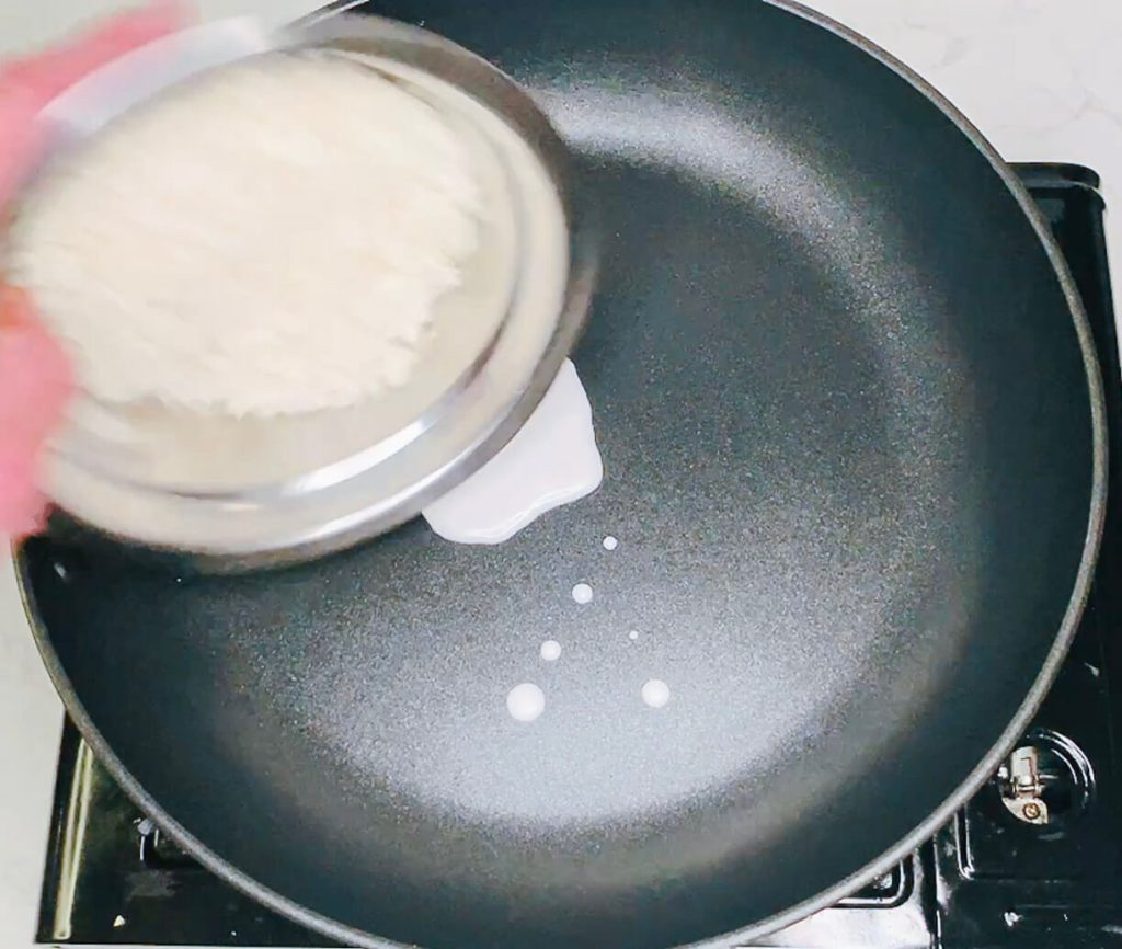 Coconut milk being poured into a hot pan.
