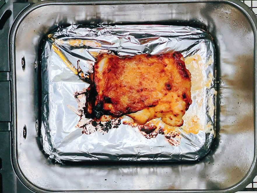 Fully cooked miso chicken in an airfryer basket, golden and caramelized.