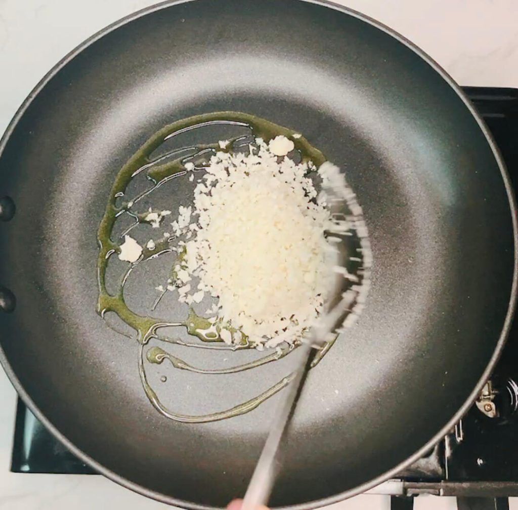 Cauliflower rice being added and stirred into hot oil in a skillet for the pan-fried method.”