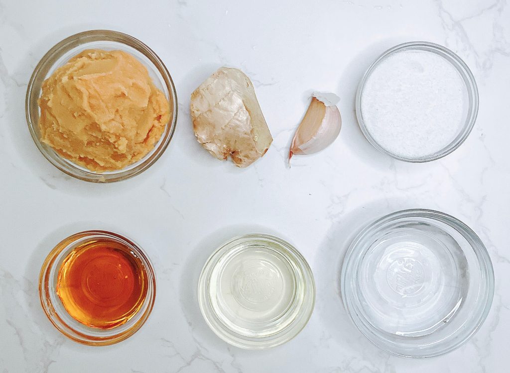 Pantry miso sauce ingredients measured out in bowls — miso paste, ginger, garlic, sugar, golden syrup, oil, and water.