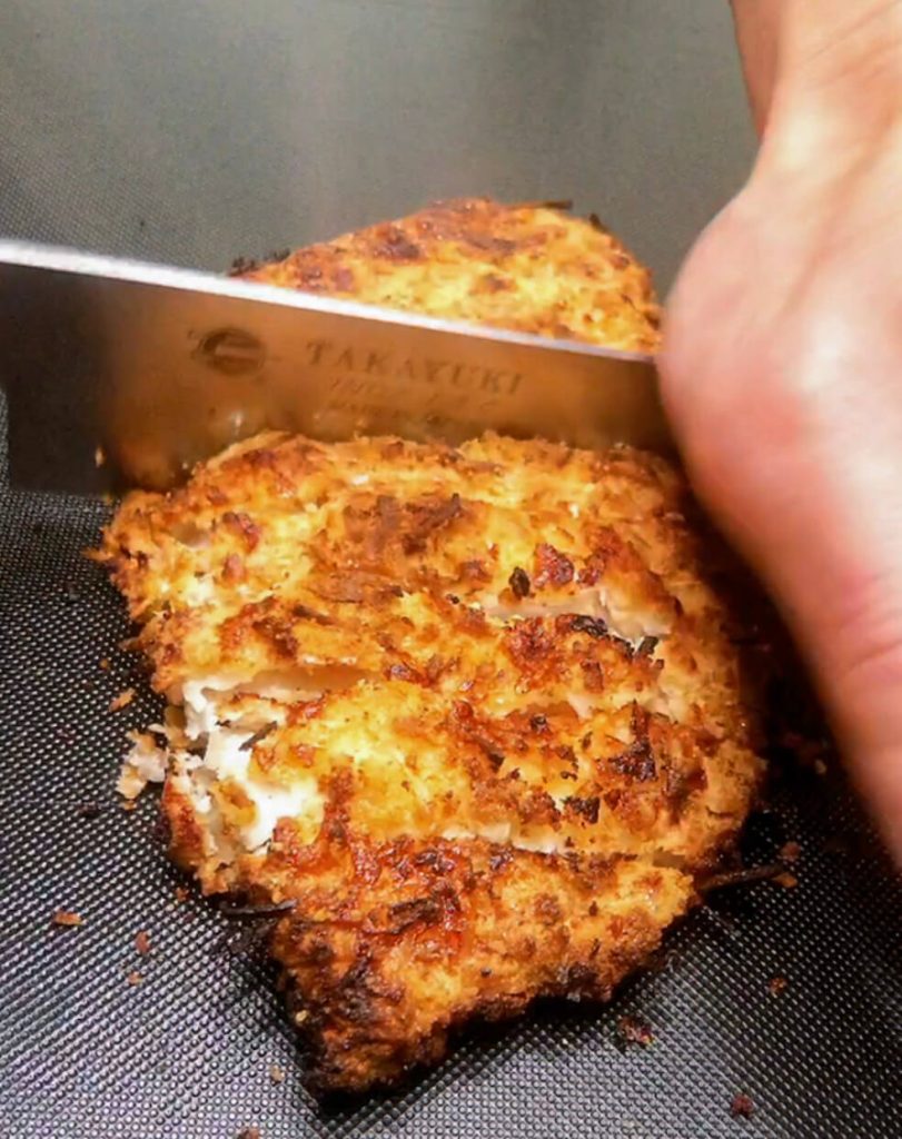 Slicing crispy chicken katsu cutlet into strips for keto chicken katsu curry.