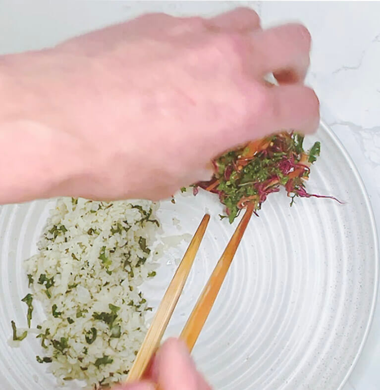 Adding coleslaw to the plate with cauliflower rice for keto chicken katsu curry.