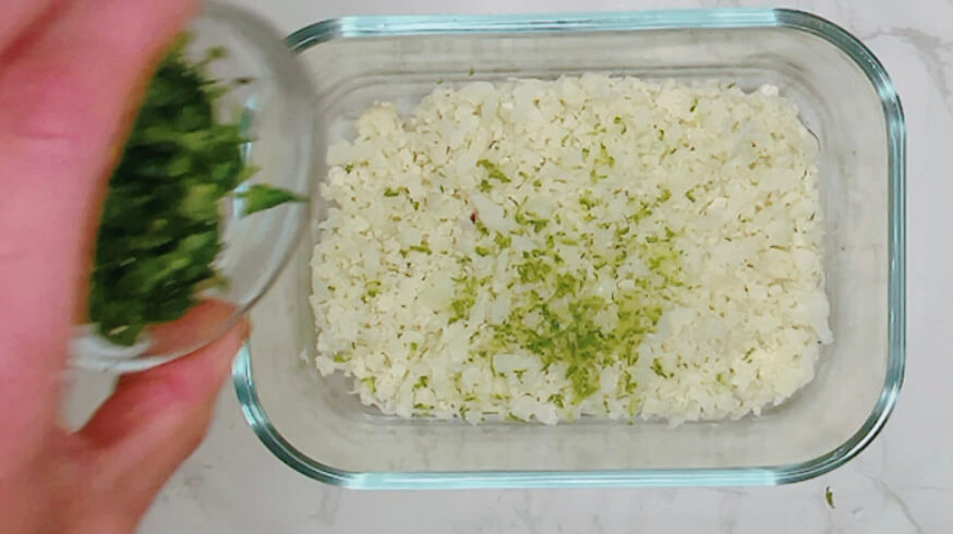 Adding chopped cilantro to cauliflower rice for lime and cilantro cauliflower rice.