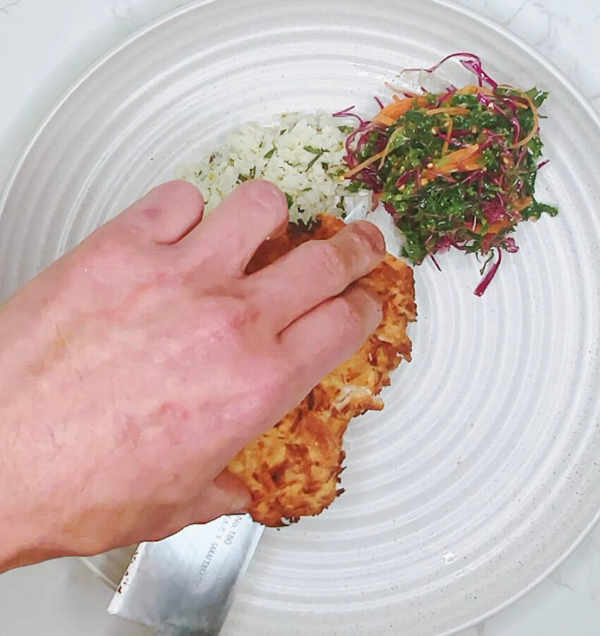 Adding coleslaw to the plate with cauliflower rice for keto chicken katsu curry.