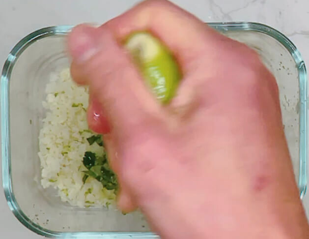 Squeezing fresh lime juice over cauliflower rice for lime and cilantro cauliflower rice.
