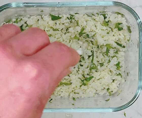 Adding salt to cauliflower rice for lime and cilantro cauliflower rice.