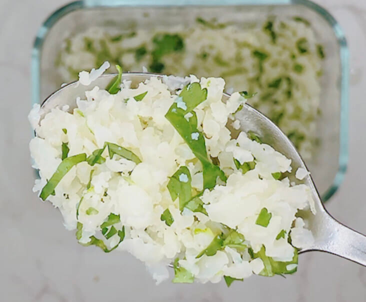 Finished lime and cilantro cauliflower rice on a spoon.