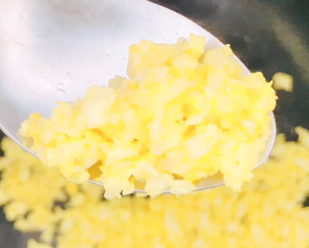“Close-up of turmeric cauliflower rice on a spoon, fluffy and golden yellow.