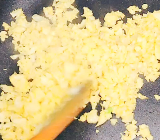 “Stir-frying turmeric cauliflower rice in a pan until fluffy and golden.”