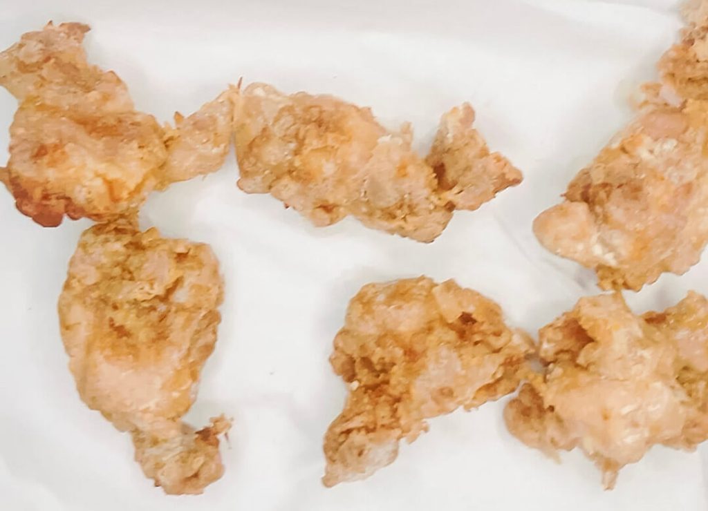 "Karaage chicken pieces after the first fry, resting on the side before the second fry."