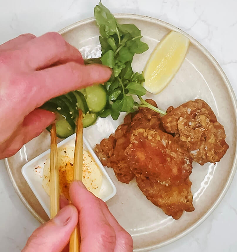 Final plated karaage chicken with dipping sauce, lemon, watercress, and quick cucumber pickles.