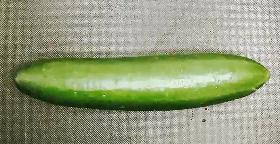 Whole cucumber on a cutting board, prepared for quick Japanese pickle.
