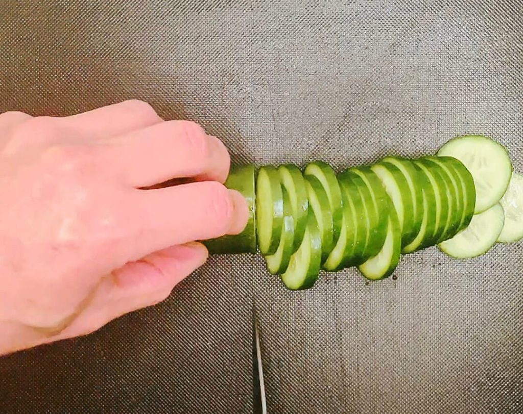 Hand slicing cucumber into pieces for quick Japanese pickles.
