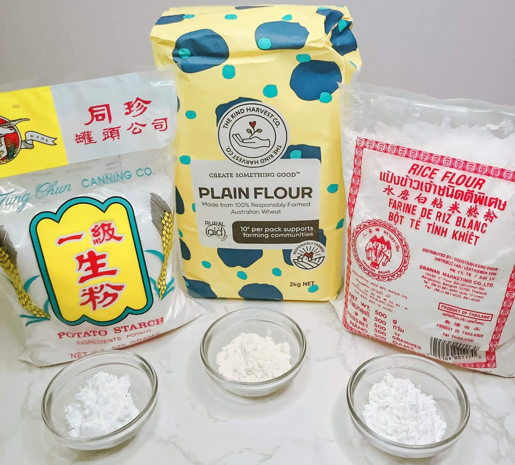 Lineup of flours for karaage chicken – potato starch, rice flour, and plain flour with packages and small bowls.