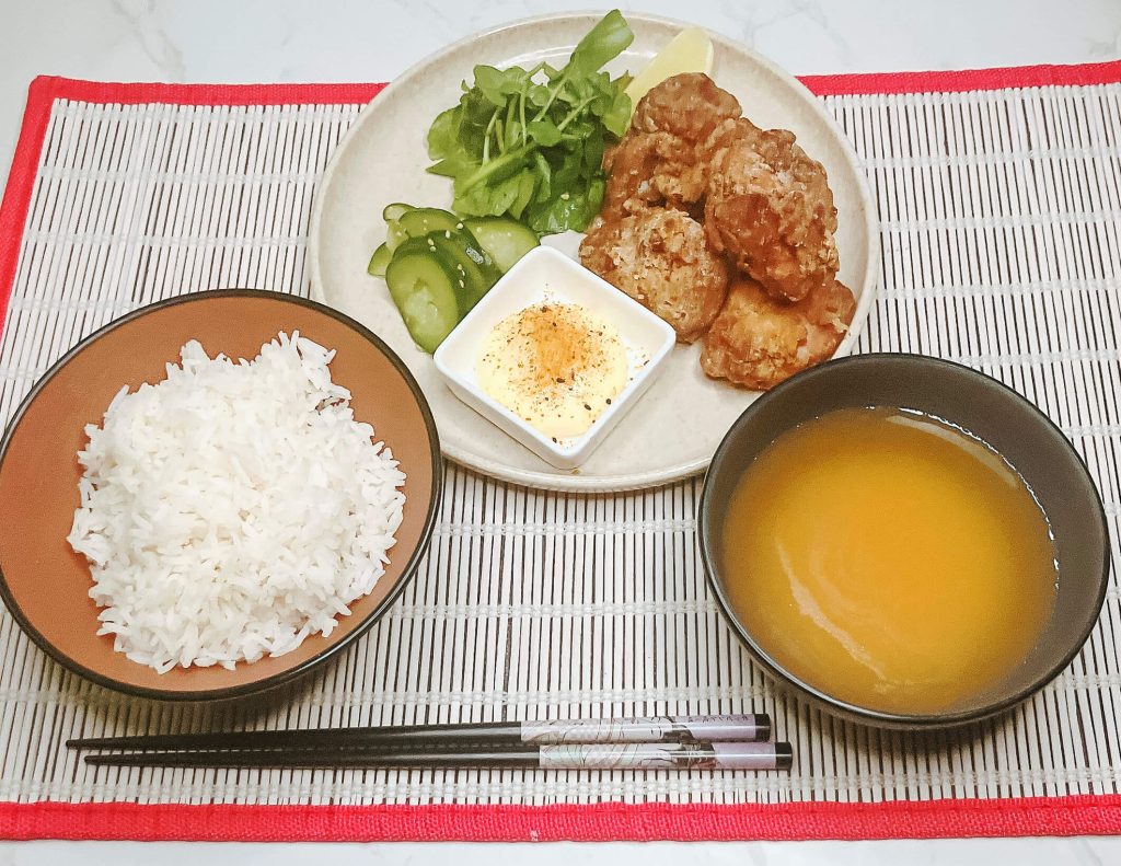 Japanese teishoku set with karaage chicken, rice, miso soup, cucumber pickles, and dipping sauce.