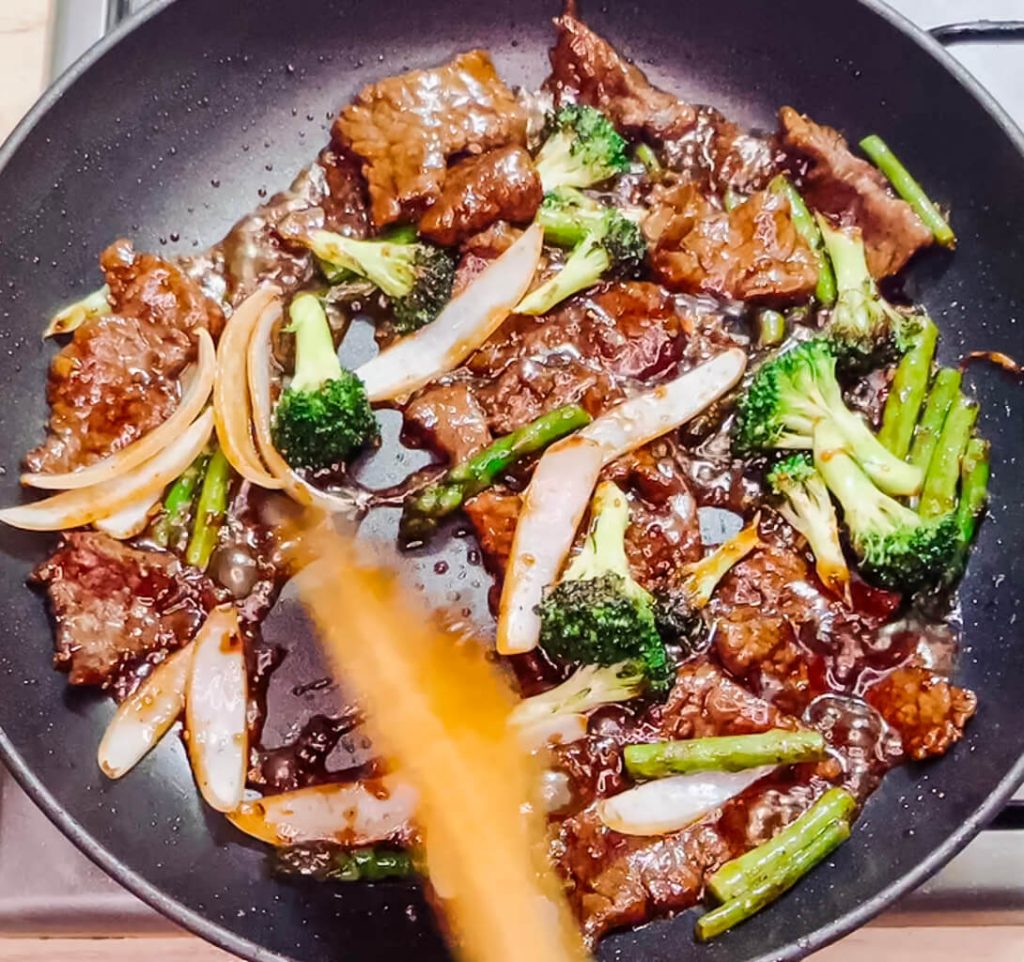 Tossing beef and vegetables in glossy teriyaki glaze for black pepper teriyaki beef.