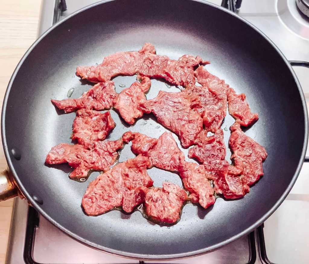 searing marinated beef slices in a hot pan for black pepper teriyaki beef.