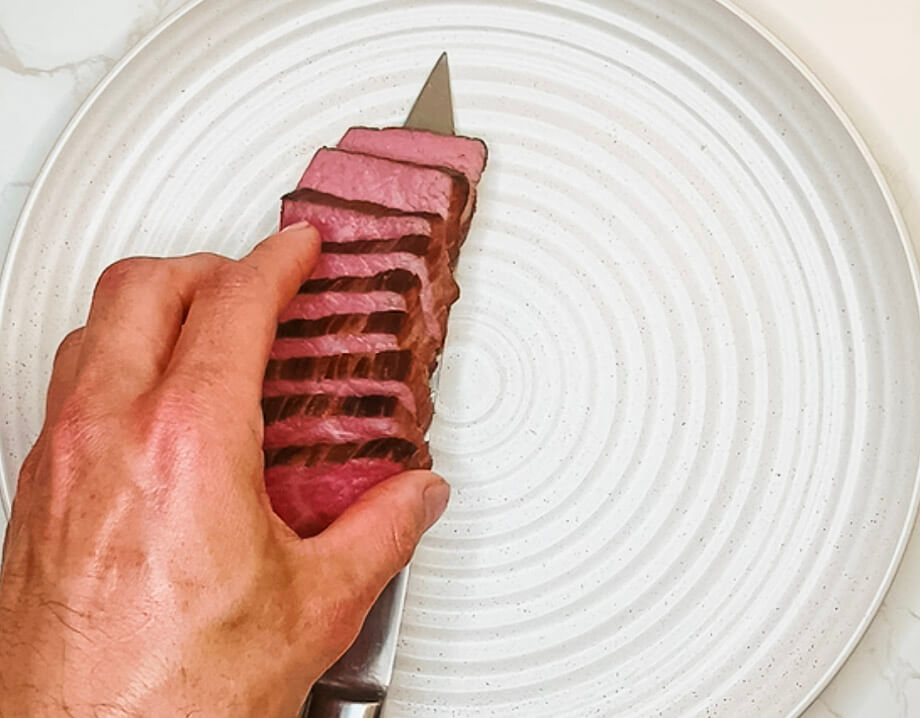 Plating sliced steak neatly on a dish for black pepper teriyaki beef.