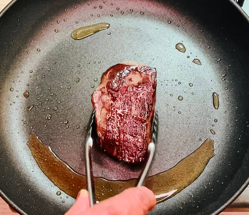 Searing a steak in a hot pan for the black pepper teriyaki beef steak version.