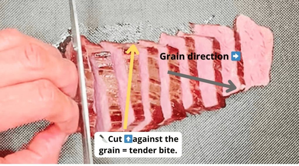 Slicing cooked black pepper teriyaki steak against the grain to show tender texture.