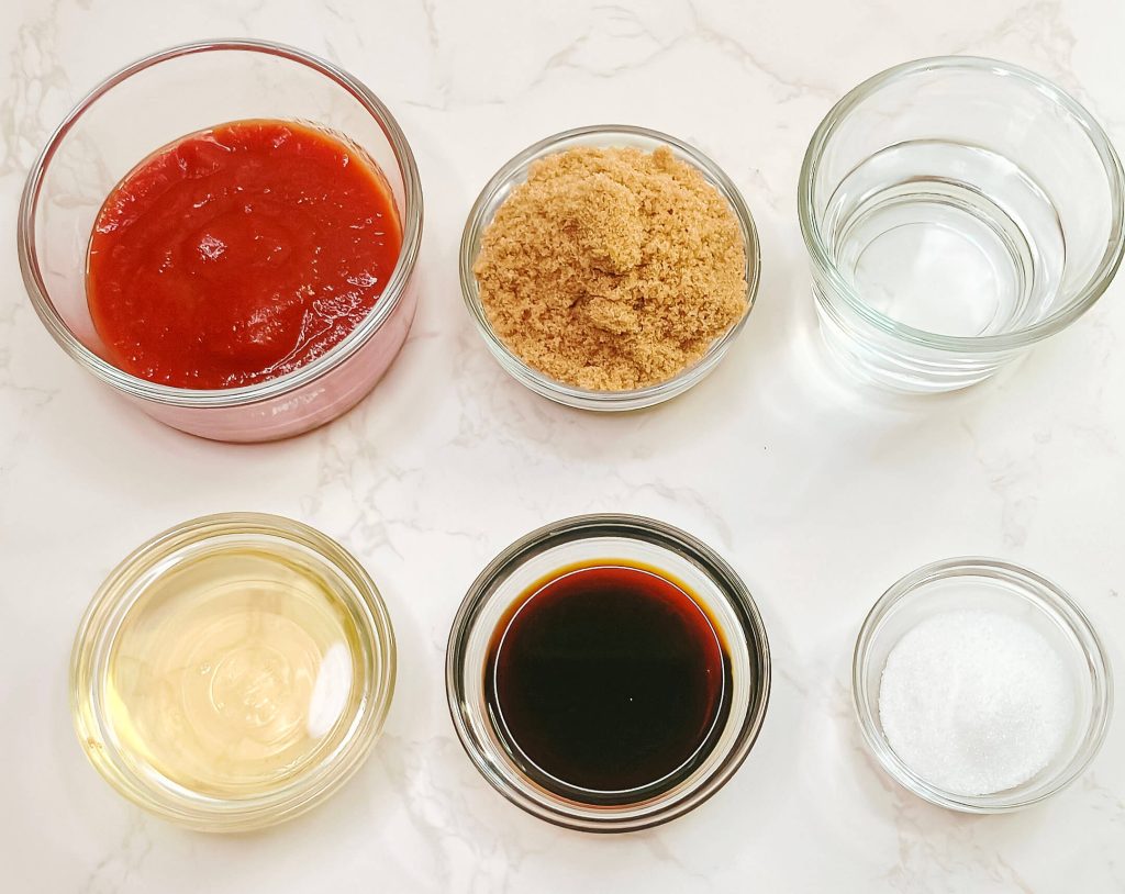 Ingredients for ketchup sweet and sour pork sauce measured in small bowls — ketchup, brown sugar, soy sauce, vinegar, and water.