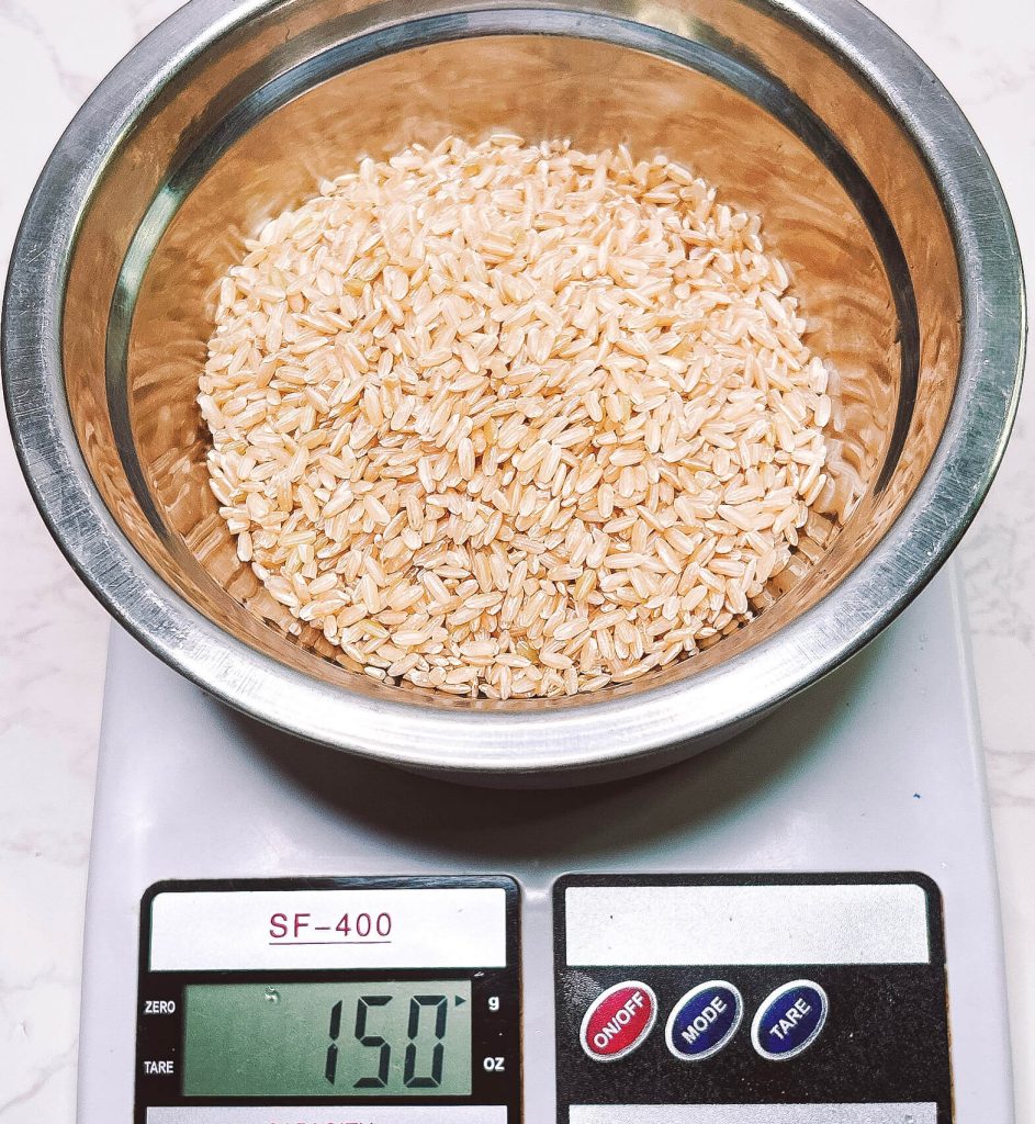 150g brown rice measured on kitchen scale in bowl