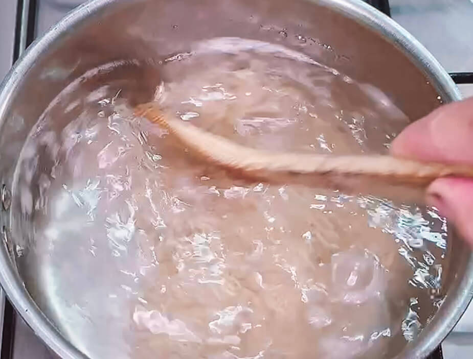 Stirring brown rice in boiling water to prevent sticking